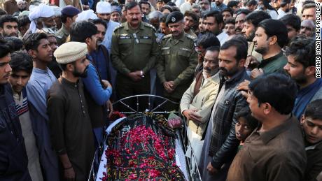 Ludzie stoją obok ciała mężczyzny, który według policji został stracony przez tłum w wiosce Tulamba w środkowym Pakistanie 13 lutego 2022 roku.