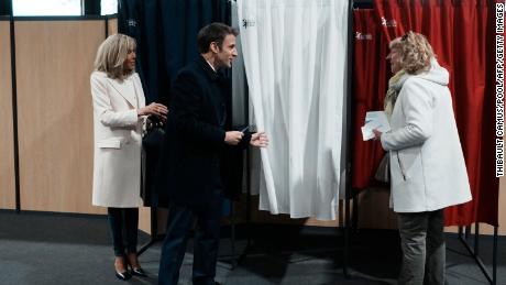 Prezydent Francji Emmanuel Macron (w środku), obok swojej żony Brigitte Macron (po lewej), rozmawia z mieszkańcem przed głosowaniem w pierwszej turze wyborów prezydenckich w niedzielę.