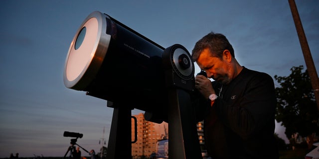 Robert Burgess, główny astronom południowego Maine, ustawia teleskop z filtrami słonecznymi, aby obserwować częściowe zaćmienie z East Party w Portland w czwartek 10 czerwca 2021 roku.