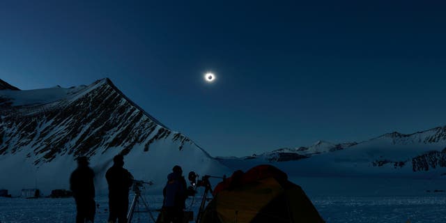 To zdjęcie opublikowane przez Imagen Chile pokazuje naukowców z Chile i Stanów Zjednoczonych, którzy przyglądają się zaćmieniu Słońca z Union Glacier na Antarktydzie 4 grudnia 2021 roku.