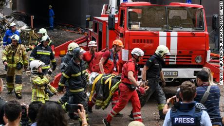 Ratownicy ewakuują osobę z budynku mieszkalnego zniszczonego w wyniku rosyjskiego nalotu w rejonie Szewczenkiwskim w Kijowie 26 czerwca 2022 r.
