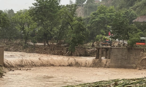 Samochód stoi obok fragmentu mostu, który został zmyty przez wody powodziowe w Qingyang w północno-zachodnich Chinach