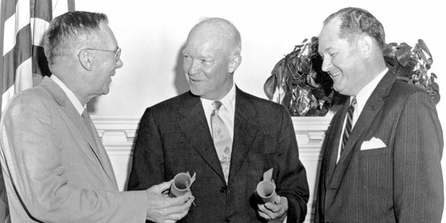 Prezydent Eisenhower z Hugh Drydenem i T. Keith Glennan, 19 sierpnia 1958. Eisenhower (w środku) przysięga dr T.  Keith Glennan (z prawej) jako pierwszy administrator NASA i dr Hugh Dryden (z lewej) jako zastępca administracyjny.  NASA została utworzona w celu prowadzenia cywilnych badań związanych z lotami kosmicznymi i lotnictwem.  (Artysta NASA.)