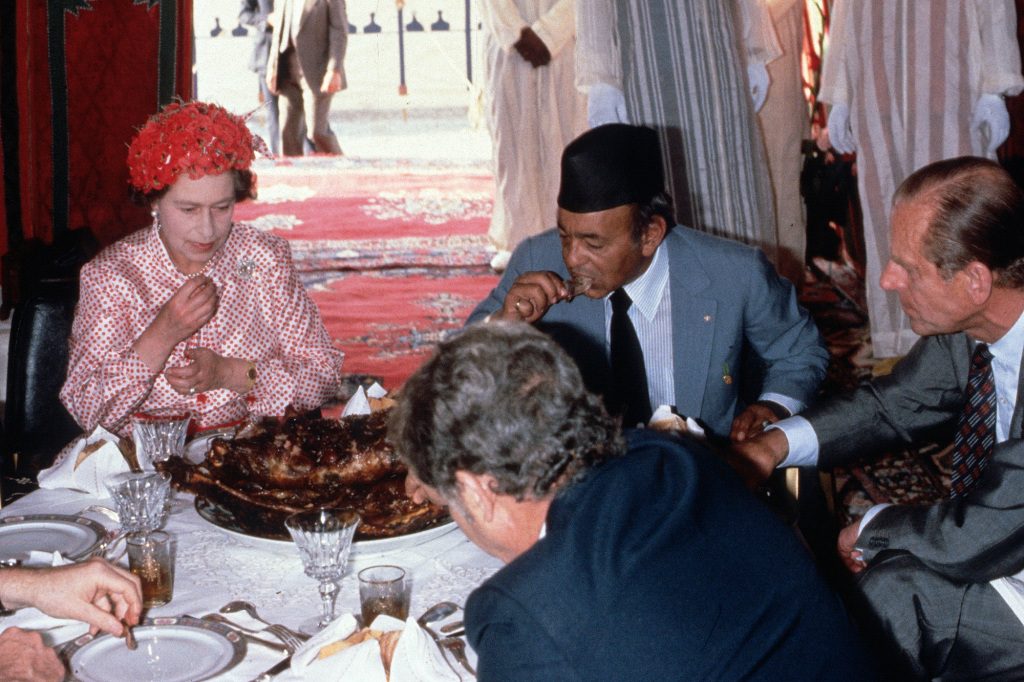 Królowa Elżbieta II, książę Filip, książę Edynburga i król Hassan jedzą rękami podczas uczty na pustyni 27 października 1980 roku w Maroku.