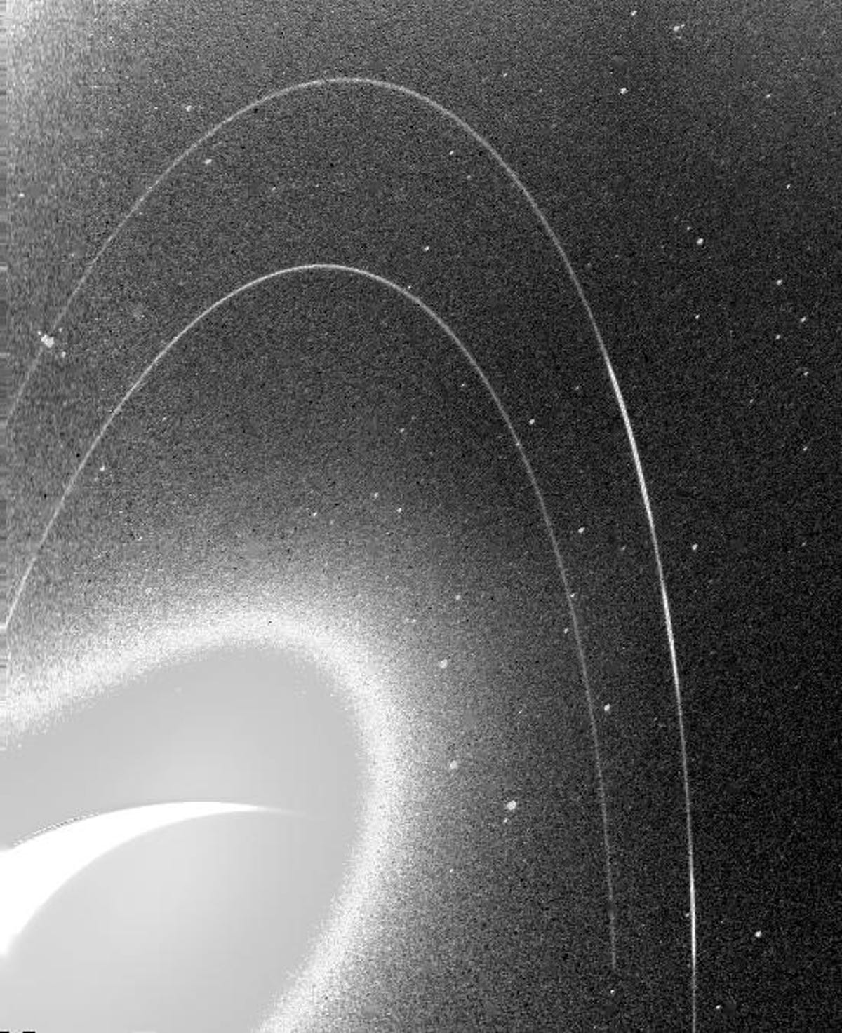 Ziarnisty czarno-biały obraz przedstawia słabe pierścienie Neptuna.