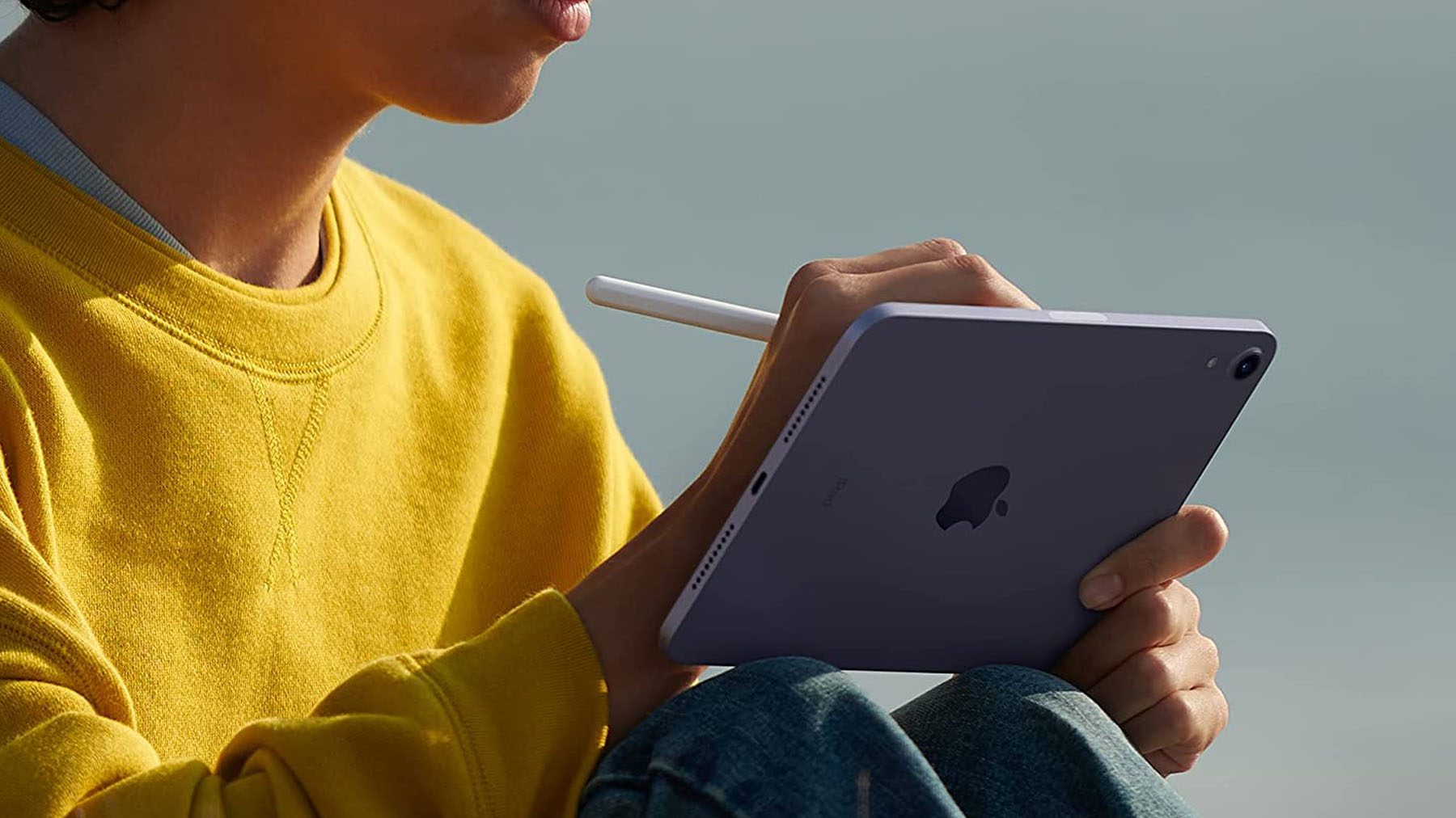 Ujęcie osoby siedzącej na iPadzie Mini podczas używania Apple Pencil