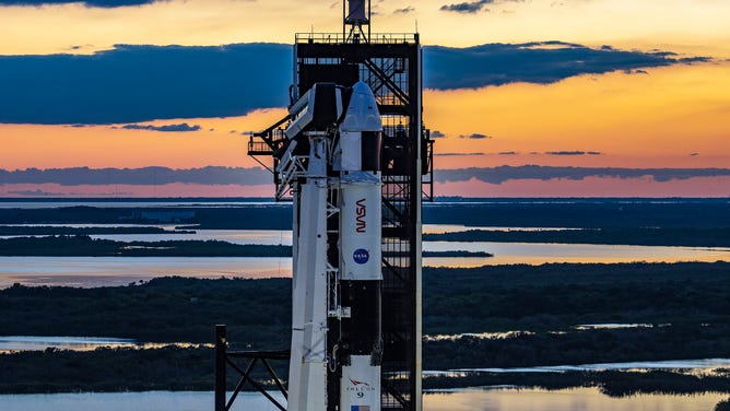 Słońce zachodzi za rakietą SpaceX Falcon 9 i statkiem kosmicznym Dragon w Kennedy Space Center na Florydzie przed startem astronauty Crew-5.